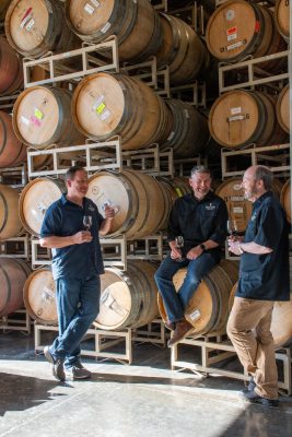 Winemakers hanging around barrels.